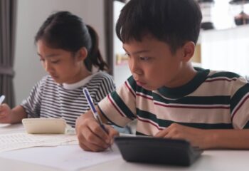 Asian elementary school children studying mathematics in class intently.