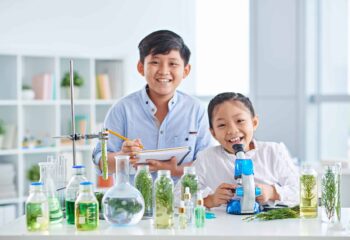 Two Vietnamese little biologists examining plants in class
