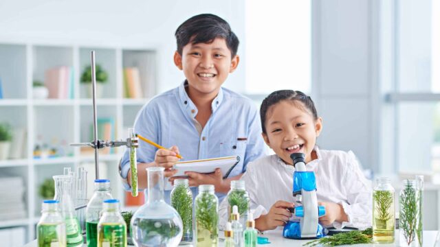 Biology class Two Vietnamese little biologists examining plants in class
