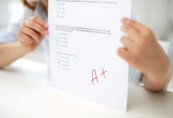 education, people, children and learning concept - girl with test paper at school
