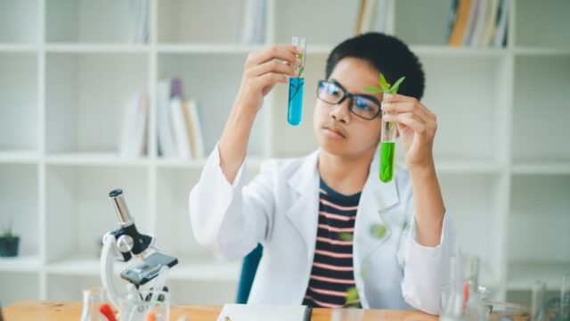 Asian male science students looking through a microscope and tes Asian male science students looking through a microscope and tests of plants in the classroom. Learning about scientific experiments on plant species.