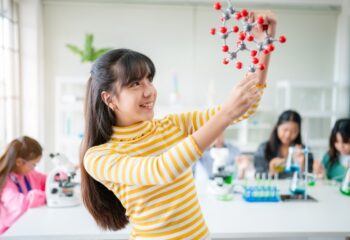 Little girl having fun time with holding molecular model learning chemistry science at classroom. Science Laboratory.